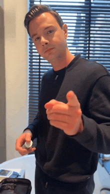 a man in a black shirt is pointing his finger