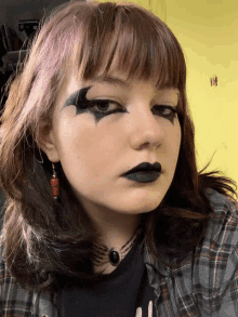 a girl wearing black lipstick and a plaid shirt