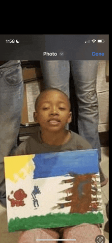 a young boy is holding a painting in front of a phone screen that says done