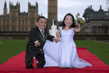 a bride and groom standing on a red carpet with a cake in the background