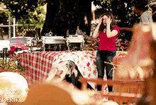 a woman in a red shirt is standing in front of a picnic table with a sign that says hogs & bears