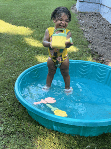 a little girl is standing in a pool of water holding a yellow bucket