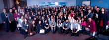 a large group of people posing for a picture with a man holding a plaque