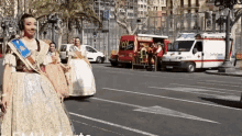 a group of women are walking down a street in front of an ambulance that says ' ambulance ' on it