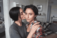 a woman kissing another woman on the cheek in a living room