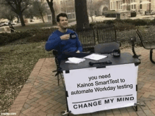 a man is sitting at a desk with a sign that says change my mind