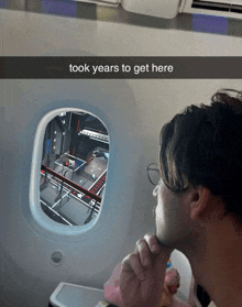 a man looking out of an airplane window with the words took years to get here above him