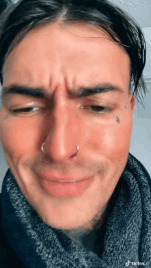 a close up of a man 's face with a nose ring