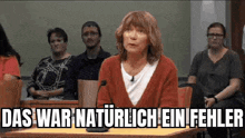 a woman is giving a speech in front of a group of people in a courtroom while sitting at a table .