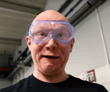 a bald man wearing a pair of safety goggles makes a funny face