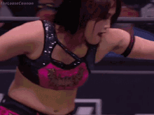 a woman in a pink and black top is standing in a ring .