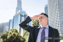 a man in a suit and tie is covering his eyes from the sun