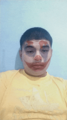 a man wearing a yellow shirt with a clown face painted on his face