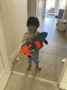 a little girl is holding a toy gun in her hand