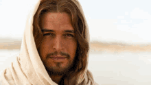 a close up of a man with long hair and a beard wearing a hooded robe .