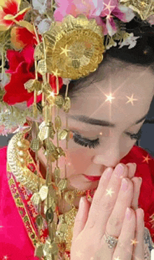 a woman wearing a red dress and gold jewelry with her hands folded