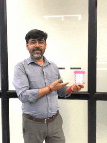 a man in a blue shirt is holding a pink cup that says ' strawberry ' on it