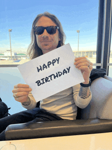 a man in sunglasses holds up a sign that says happy birthday