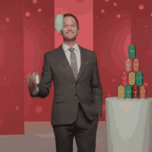 a man in a suit is standing in front of a stack of soda cans with smiley faces on them