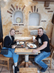 a man and a woman are sitting at a table eating food