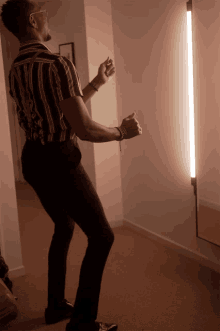 a man in a striped shirt is dancing in front of a light