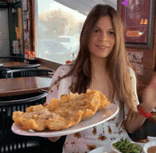 a woman is holding a plate of food in front of a sign that says ' chicken ' on it