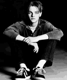 a black and white photo of a young man sitting down