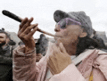 a woman in a pink jacket is smoking a marijuana cigarette .