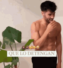 a shirtless man is standing in front of a plant with a plant in the background .