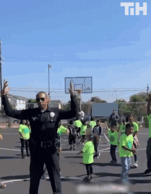 a police officer stands in front of a group of children wearing green shirts with the letters th on them