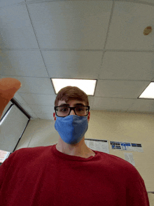 a man wearing glasses and a blue face mask is standing in a room