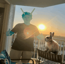 a boy and a rabbit standing on a balcony at sunset