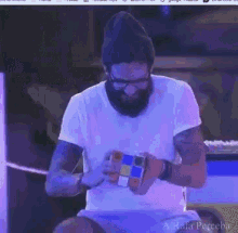 a man with a beard is holding a rubik 's cube in his hands