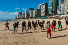 a group of people are dancing on a beach and one of them is wearing a shirt that says ' academia ' on the front