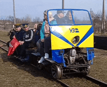 a group of people are riding on a blue and yellow vehicle that says vb on the front