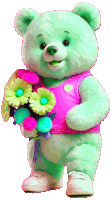 a green teddy bear wearing a pink shirt holds a bunch of flowers