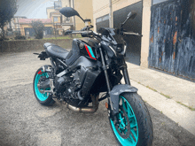 a black yamaha motorcycle with blue wheels is parked in front of a garage