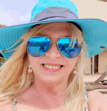 a woman wearing a blue hat and blue sunglasses smiles for the camera