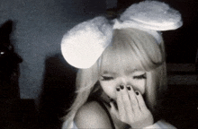 a woman is wearing bunny ears and covering her face with her hand .