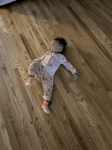 a baby is laying on a wooden floor wearing socks