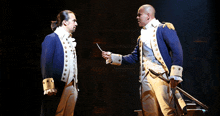 two men in military uniforms are standing next to each other on stage