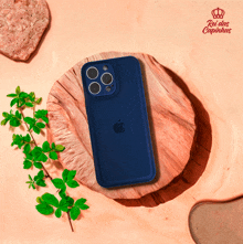 a blue iphone is sitting on a wooden block with a rei das capinhas logo behind it