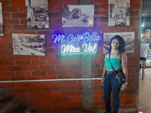 a woman stands in front of a sign that says " mi cali bella mira vel "