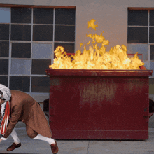 a man is running towards a dumpster with flames coming out of the top