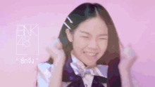 a girl wearing a bow tie and a bnk 48 logo on a pink background