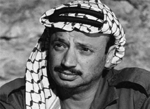 a black and white photo of a man wearing a turban and a scarf around his head .