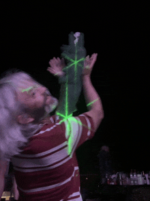 a man in a red and white striped shirt is holding a green object in his hand