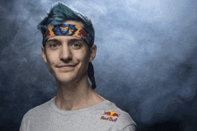 a young man with blue hair is wearing a red bull headband and smiling .