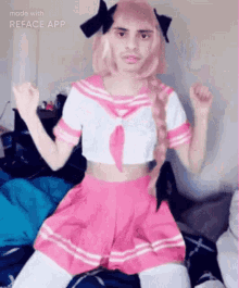 a man dressed as a girl is sitting on a bed with his arms in the air