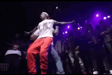 a man is dancing on a stage in front of a crowd in a dark room .